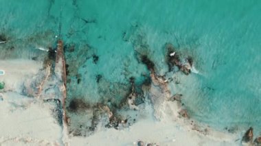 Video of drone views of a cliff next to a sea with crystal clear waters