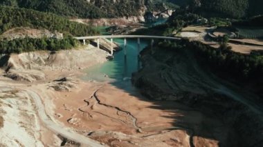 Video of drone views of a mountain landscape with a river crossing a bridge