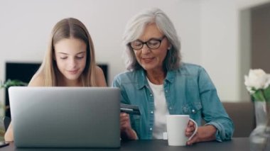 Video of cute granddaughter teaching her grandmother to play video games on the console on sofa at home