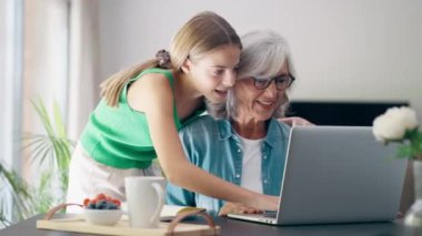 Video of cute granddaughter teaching her grandmother to play video games on the console on sofa at home