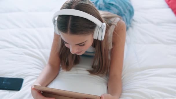 Yatakta Oturmuş Akıllı Telefonuyla Müzik Dinleyen Güzel Bir Genç Kızın — Stok video