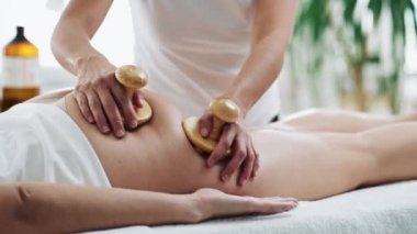 Video of therapist woman doing back massage with wooden balls to a pretty woman on the spa center