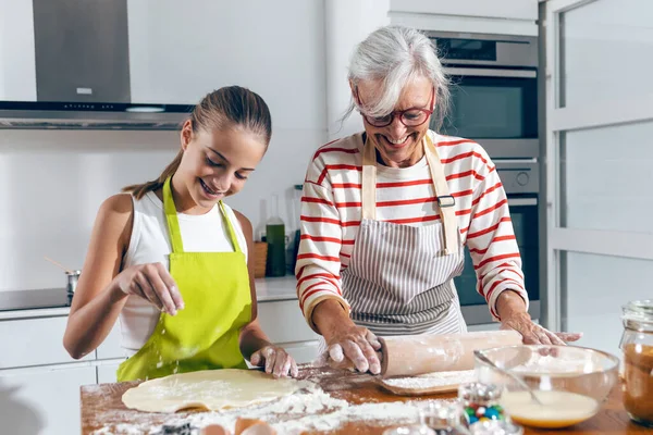 Shot of happy family grandmother and granddaughter baking cookies in the kitchen