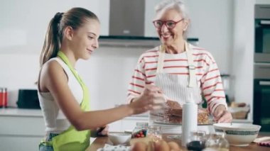 Video of happy family grandmother and granddaughter making chocolate cake in the kitchen