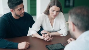 Ev planlarını elektronik tablette gösteren emlakçının videosu. Ofisteki evi almak için çiftle konuşurken..