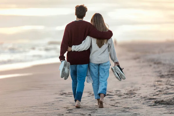 一对年轻貌美的恋人在寒冷的冬日里在沙滩上漫步的画像 — 图库照片