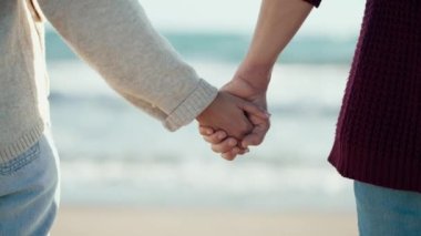 Soğuk bir kışta kumsalda yürürken el ele tutuşan güzel çiftin yakın çekim videosu..
