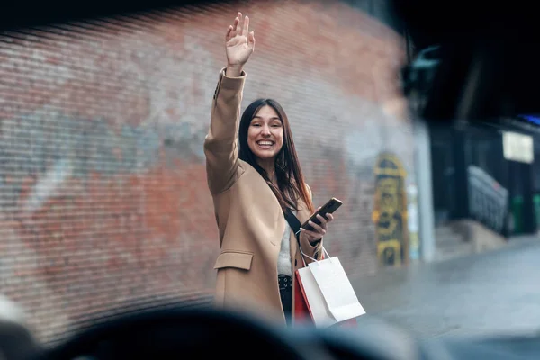 在城市里 一个微笑的女人举起手叫出租车站在路上 — 图库照片