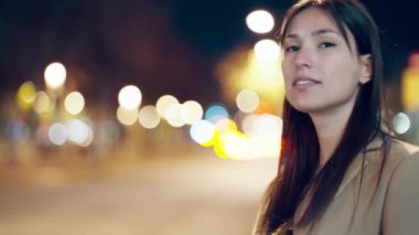 Çekici, gülümseyen genç bir kadının gece sokakta yürüdüğü bir video..