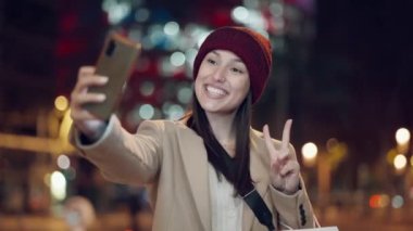 Genç kadın turistin gülerken ve cep telefonuyla selfie çekerken çekilmiş videosu.