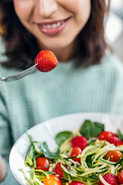 美しい笑顔の女性のショット自宅でテーブルの上に座って健康的なサラダを食べる — ストック写真