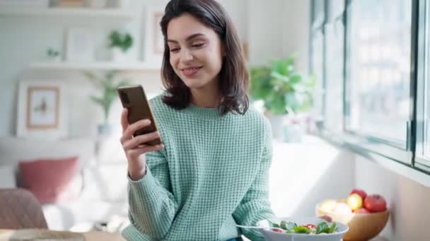 Evdeki Oturma Odasında Cep Telefonunu Kullanırken Bir Kase Salata Yiyen — Stok video