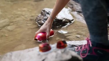 Yakın plan kadın ellerinin matarayı dağdaki bir nehirde tatlı suyla doldurduğu video.