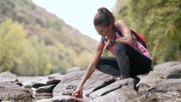 山の上の川で新鮮な水で食堂を充填クローズアップ女性のビデオ — ストック動画