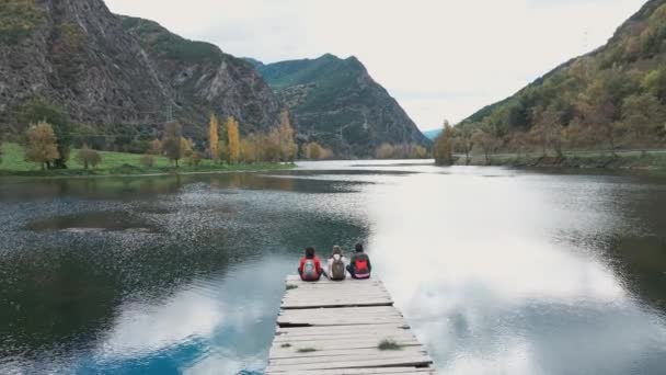 美丽的家庭坐在湖上的码头上看着地平线的视频 — 图库视频影像