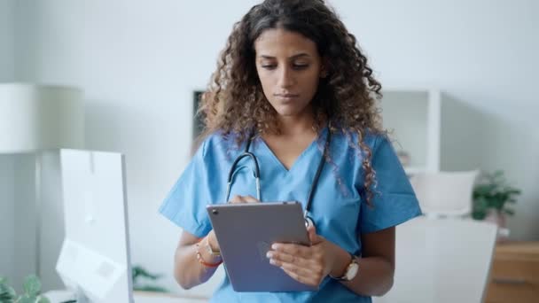 在医院会诊时 年轻美丽的女医生一边拿着数码平板电脑 一边看着镜头的视频 — 图库视频影像