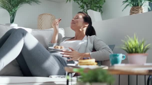 ビデオの美しいです幸せな妊娠中の女性でパンティー食べるチョコレートトリュフ嘘オンソファ — ストック動画