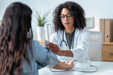 Güzel bir kadın doktor kalp ve kan basıncını ölçerken genç bir hastaya tıbbi muayenede bakıyor.