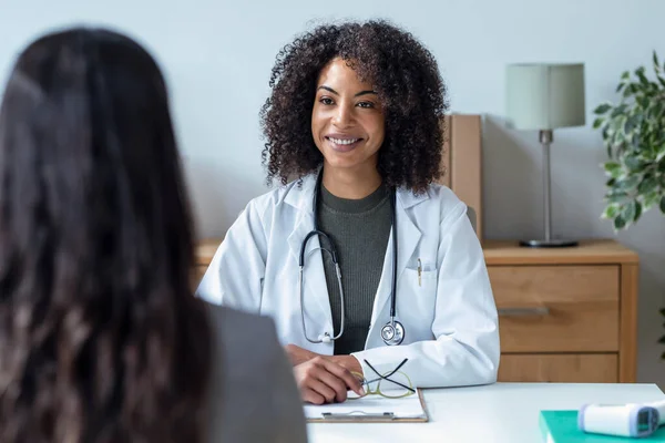 stock image Shot of beautiful cheerful female doctor talking while explaining medical treatment to patient in the consultation.