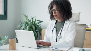 Danışmanlıkta dizüstü bilgisayar üzerinde çalışırken cep telefonunu kullanan kendine güvenen bir kadın doktorun videosu..