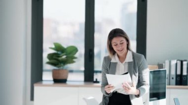 Modern ofisteki masada oturmuş notları okurken çalışan zarif bir iş kadınının videosu.