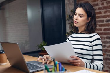Modern bir ofisin planlarını çalışırken dizüstü bilgisayarla çalışan mimar kadının fotoğrafı..