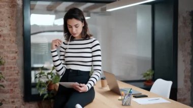 Modern bir ofisteki bir masada otururken dijital tabletle çalışan mimar kadının videosu..