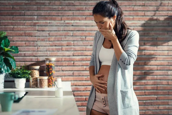 自宅でキッチンでヨーグルトを食べながら吐き気とうんざり妊婦のショット — ストック写真