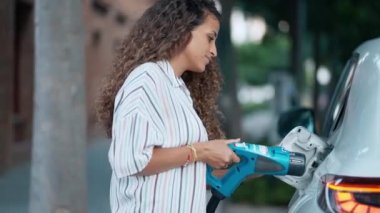 Elektrikli benzin istasyonunda güzel bir kadının elektro arabayı şarj ettiği video.