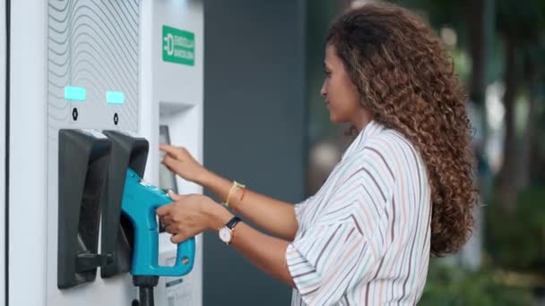 電気ガソリンスタンドで電気自動車を充電する美しい女性のビデオ — ストック動画