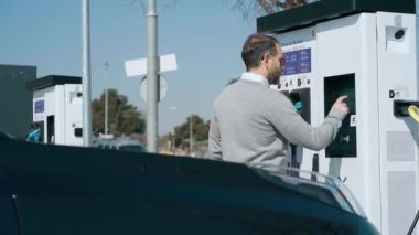Elektro arabayı elektrik istasyonunda şarj eden zarif adamın videosu.