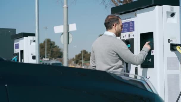 エレガントな男のビデオ電気ガソリンスタンドで電気自動車を充電 — ストック動画