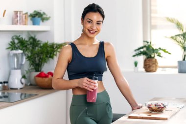 Evdeki mutfakta sağlıklı protein içeceği içen atletik bir kadın.