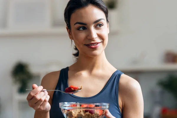 自宅で台所で果物とムエリの健康的なボウルを食べる運動選手のショット — ストック写真