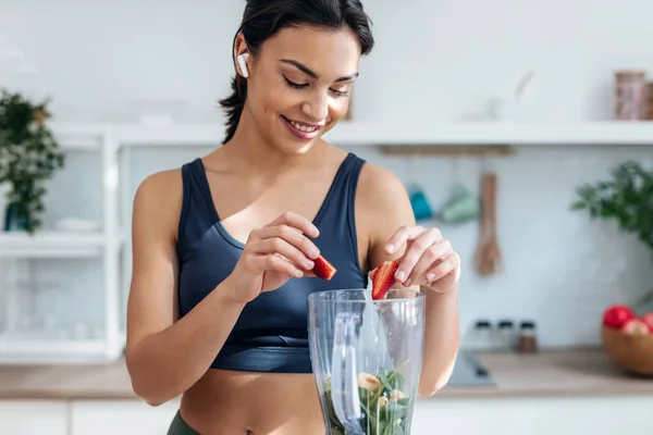 Foto Mujer Atlética Preparando Smothie Con Verduras Frutas Mientras Escucha — Foto de Stock