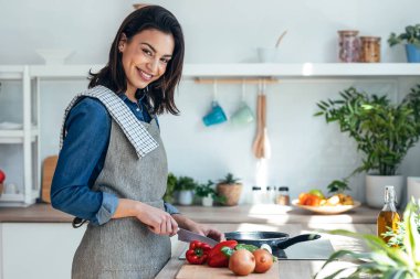 Shot of healthy young woman cutting fresh vegetables while cooking healthy food in the kitchen at home.