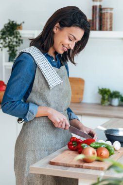 Shot of healthy young woman cutting fresh vegetables while cooking healthy food in the kitchen at home.