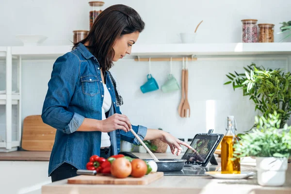 건강에 음식을 요리하고 가정에서 요리하는 디지털 태블릿을 사용하는 아름다운 여성의 — 스톡 사진