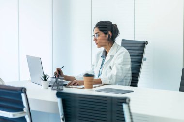 Tıbbi konsültasyonda kulaklıkla konuşurken güzel bir kadın doktorun görüntüsü..