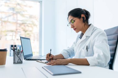 Tıbbi konsültasyonda kulaklıkla konuşurken güzel bir kadın doktorun görüntüsü..