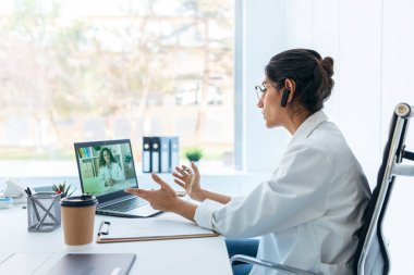 Tıbbi konsültasyonda kulaklıkla konuşurken güzel bir kadın doktorun görüntüsü..