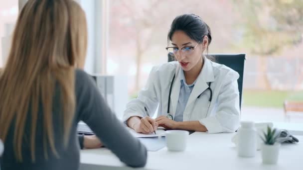 診察中に患者さんに医療を説明しながら話す美しい陽気な女性医師のビデオ — ストック動画
