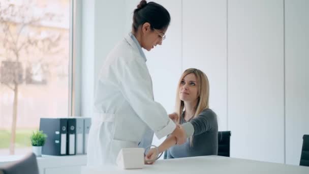 在诊疗过程中 美丽的女医生一边照顾年轻病人一边测量心脏和血压的视频 — 图库视频影像