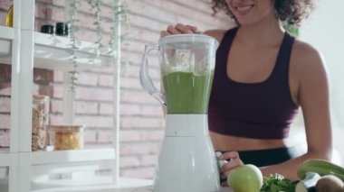 Evdeki mutfakta sebze yeşili smoothie yapan genç bir kadının videosu..