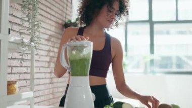 Evdeki mutfakta sebze yeşili smoothie yapan genç bir kadının videosu..