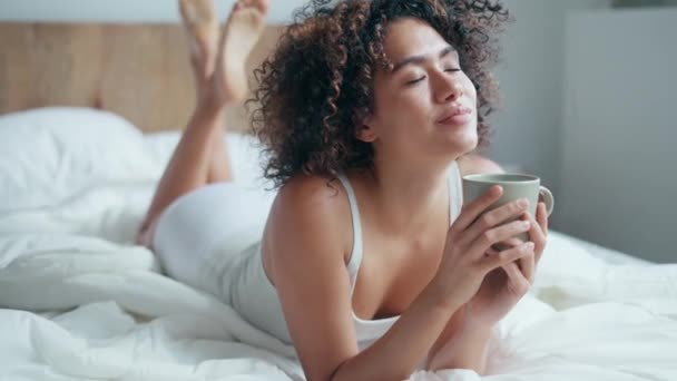 ベッドの上で滞在中にコーヒーを飲みながら下着姿の美しい女性のビデオ — ストック動画
