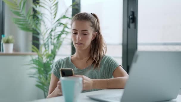 Evde Dizüstü Bilgisayarla Çalışırken Cep Telefonunu Kullanan Konsantre Genç Kadınının — Stok video