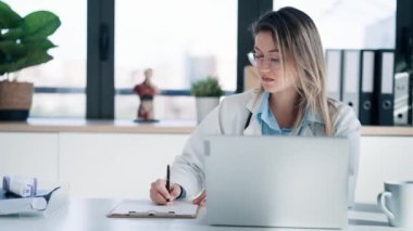 Ciddi bir kadın doktorun tıbbi konsültasyonda laptopuyla çalışırken videosu..