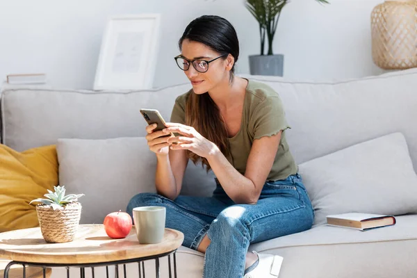 Tiro Mujer Hermosa Usando Teléfono Inteligente Mientras Relaja Sofá Casa —  Fotos de Stock