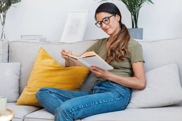 Snímek Sebevědomé Ženy Čtení Knihy Zatímco Sedí Pohovce Doma — Stock fotografie